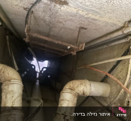 צינורות מתכת חלודים בתקרה עם נזילות מים